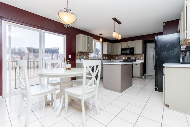 kitchen with hanging light fixtures, light countertops, backsplash, a center island, and black appliances