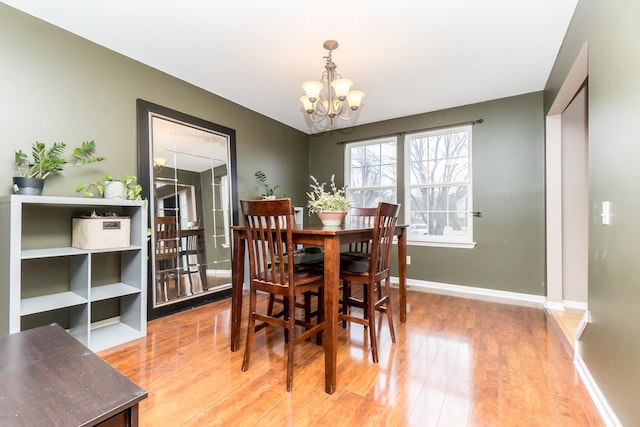 dining space featuring light wood-style floors, baseboards, and an inviting chandelier