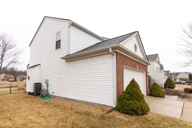 view of side of home featuring brick siding, a yard, concrete driveway, fence, and a garage