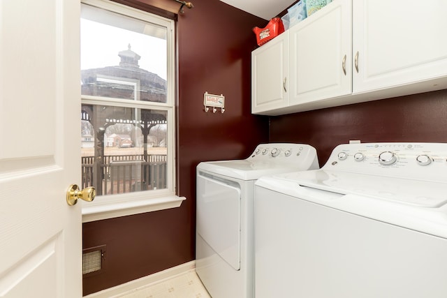 washroom with washer and dryer, cabinet space, and baseboards