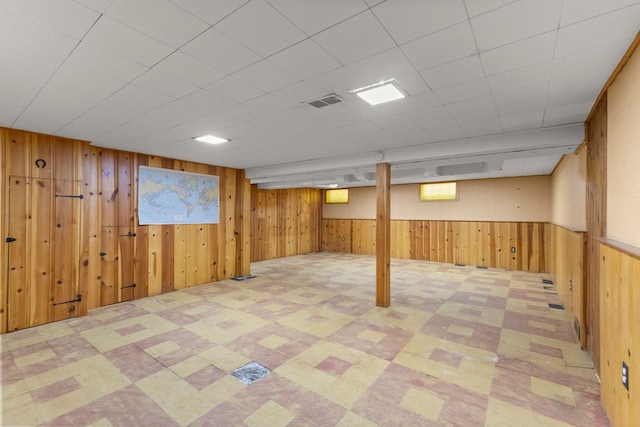 below grade area with a wainscoted wall, wood walls, visible vents, and tile patterned floors