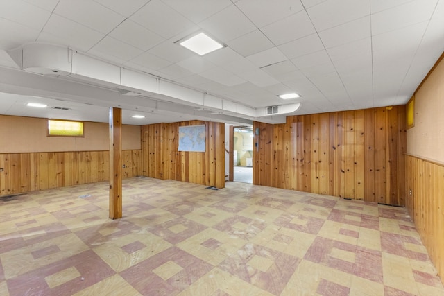 below grade area featuring visible vents, wood walls, and tile patterned floors