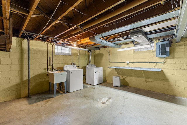 basement with a sink, washing machine and dryer, and electric panel