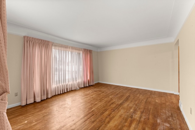 unfurnished room featuring crown molding, wood finished floors, and baseboards