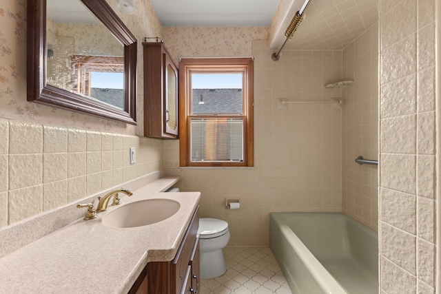 bathroom featuring toilet, vanity, tile walls, and wallpapered walls