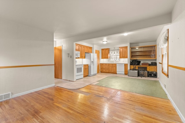 unfurnished living room with visible vents, light wood-style flooring, and baseboards