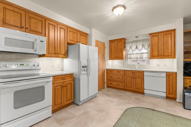 kitchen featuring light floors, white appliances, and brown cabinetry