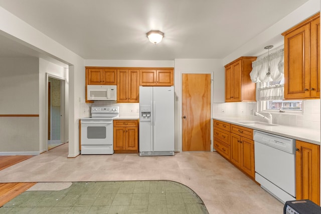 kitchen featuring brown cabinets, white appliances, light floors, and a sink