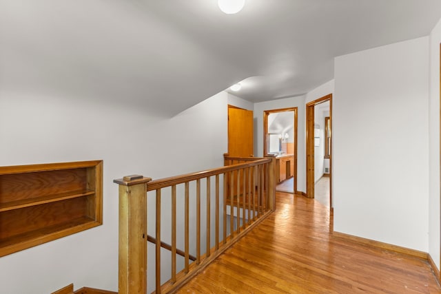 corridor featuring light wood-style floors, baseboards, and an upstairs landing