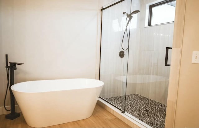 full bathroom featuring a stall shower, a soaking tub, and wood finished floors