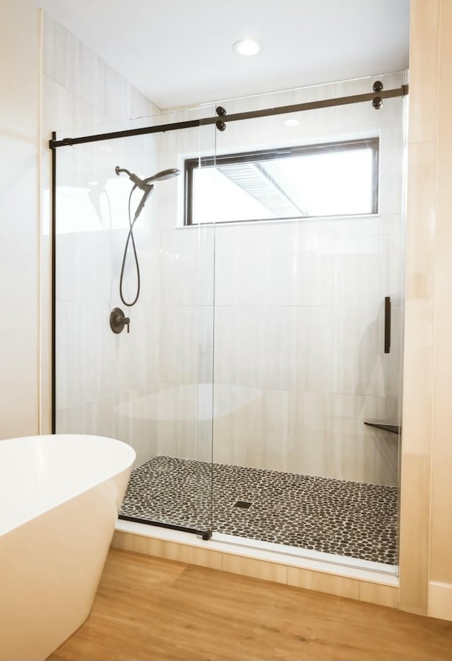 bathroom with a freestanding tub, a shower stall, and wood finished floors