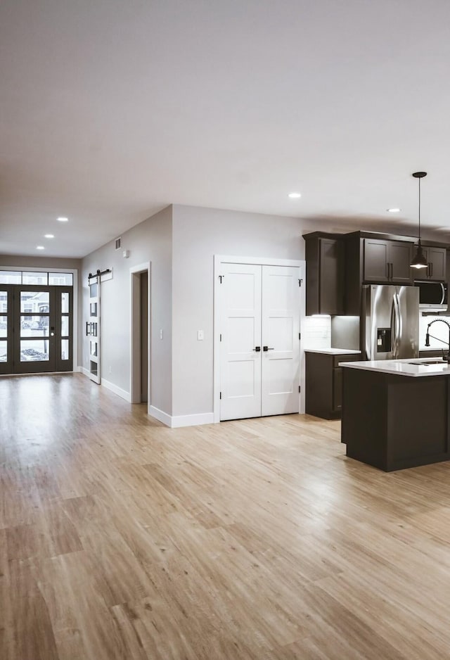 kitchen with a barn door, appliances with stainless steel finishes, open floor plan, light countertops, and light wood-style floors