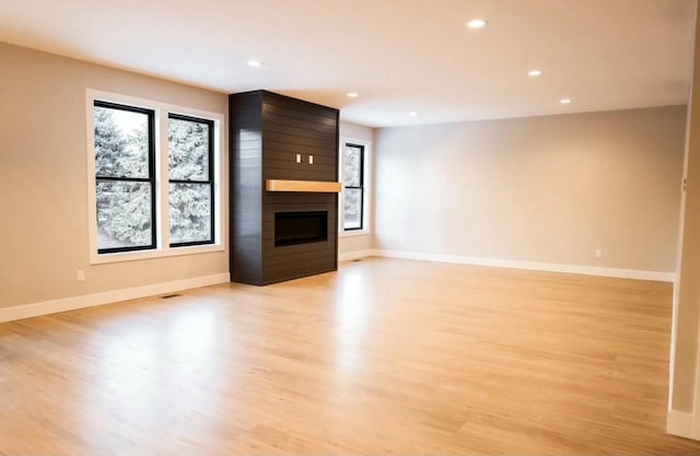 unfurnished living room featuring a wealth of natural light, a fireplace, and baseboards