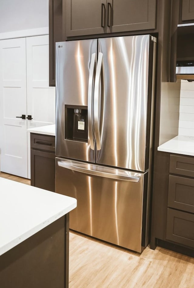 kitchen with light countertops, dark brown cabinetry, light wood finished floors, and stainless steel fridge with ice dispenser