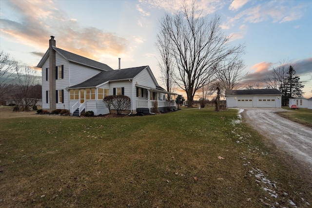 property exterior at dusk featuring a garage, an outdoor structure, a chimney, and a lawn