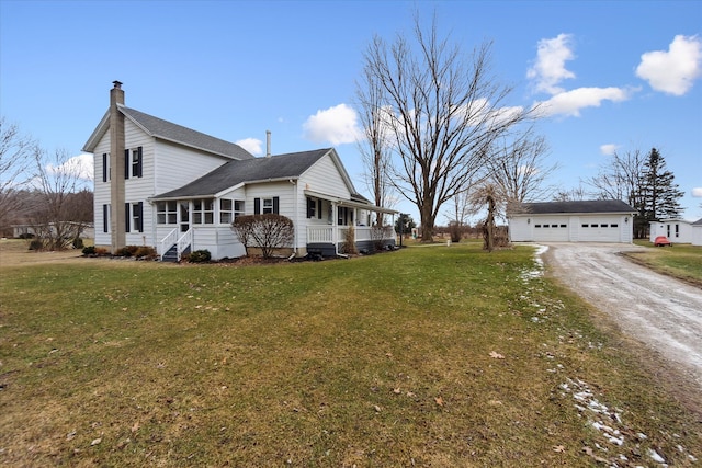 view of side of property featuring a garage, a chimney, covered porch, a yard, and an outdoor structure