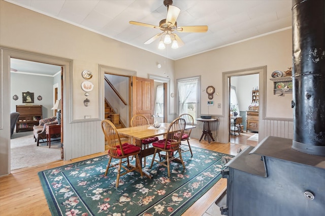 dining space with light wood-type flooring, a wainscoted wall, and crown molding