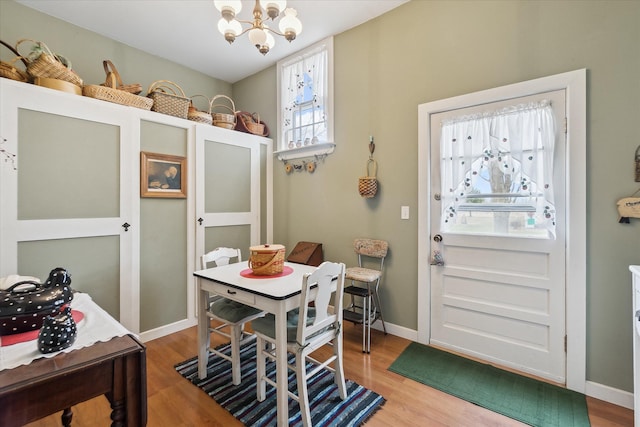 dining space with wood finished floors, baseboards, and an inviting chandelier