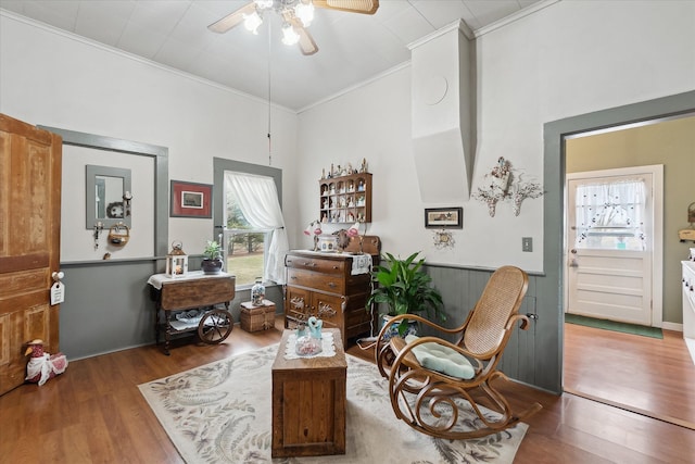 living area featuring ceiling fan, ornamental molding, and wood finished floors