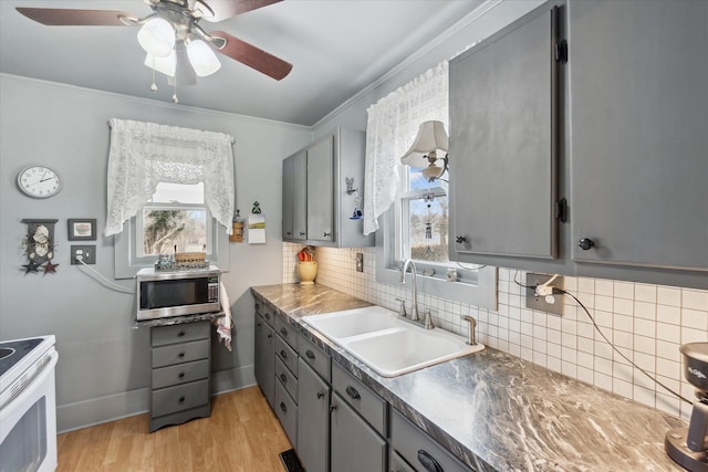 kitchen with gray cabinets, stainless steel microwave, a sink, and white electric range oven