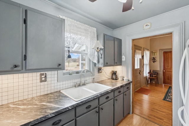 kitchen featuring light wood-style floors, gray cabinets, a sink, and tasteful backsplash