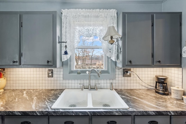 kitchen featuring tasteful backsplash, gray cabinets, and a sink