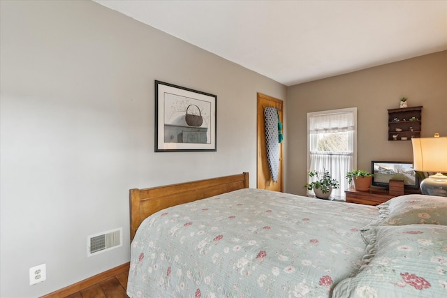 bedroom with baseboards, visible vents, and wood finished floors