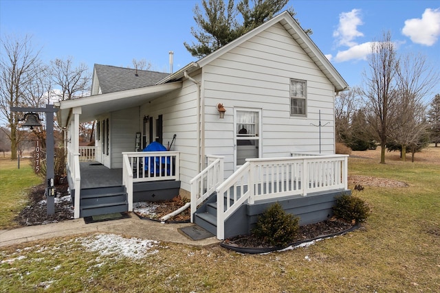 back of property with a shingled roof, a porch, and a yard