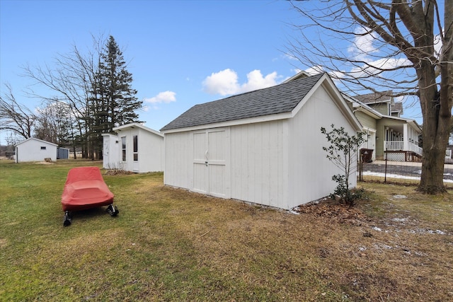 view of side of property featuring roof with shingles, a yard, an outdoor structure, and a shed