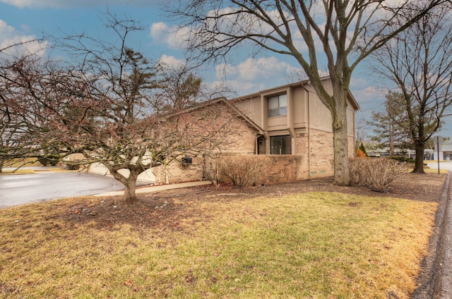 view of front facade featuring an attached garage, brick siding, driveway, and a front lawn