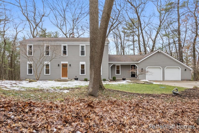 colonial home with driveway, a chimney, and an attached garage