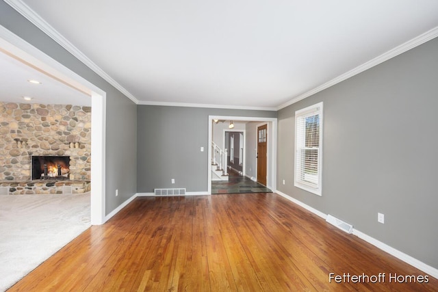 unfurnished living room featuring baseboards, a fireplace, visible vents, and crown molding