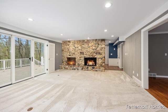 unfurnished living room with a stone fireplace, recessed lighting, carpet flooring, visible vents, and baseboards