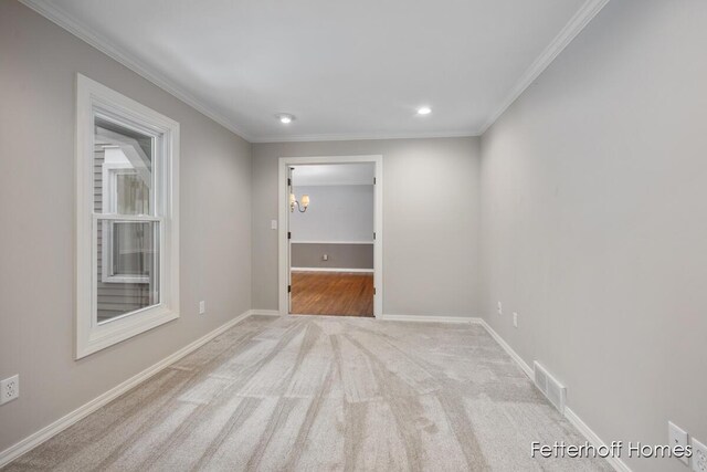 spare room with baseboards, visible vents, and ornamental molding