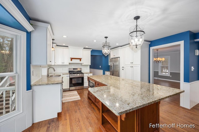 kitchen with dark wood-type flooring, appliances with stainless steel finishes, a kitchen island, and a sink