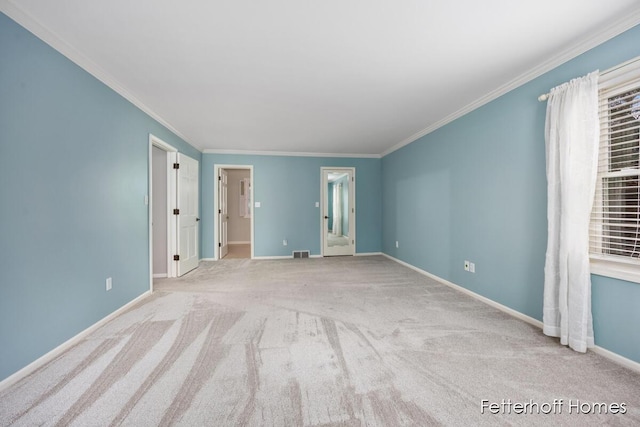 carpeted spare room featuring crown molding, visible vents, and baseboards