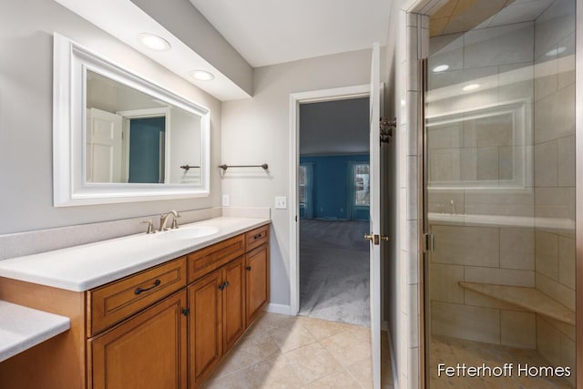 full bath featuring baseboards, tile patterned flooring, a tile shower, vanity, and recessed lighting