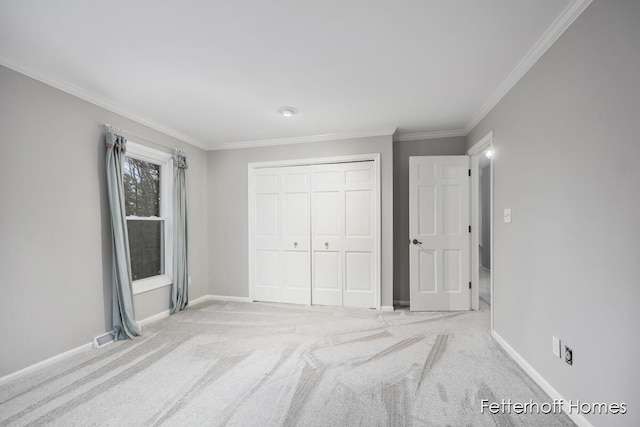 unfurnished bedroom featuring crown molding, carpet floors, a closet, and baseboards