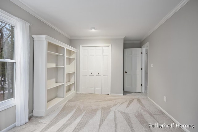 unfurnished bedroom with carpet, a closet, baseboards, and crown molding