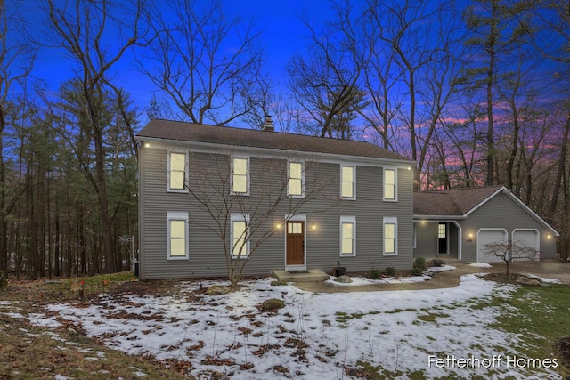 colonial inspired home with a garage and a chimney