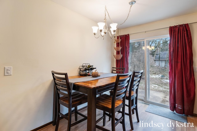 dining room with a chandelier, baseboards, and wood finished floors