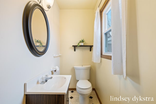 bathroom with baseboards, vanity, and toilet