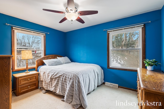 bedroom with ceiling fan, multiple windows, carpet, and visible vents