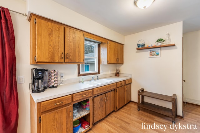 kitchen with open shelves, a sink, light countertops, and brown cabinets