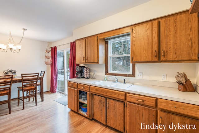 kitchen with light countertops, light wood-style floors, a sink, and brown cabinets