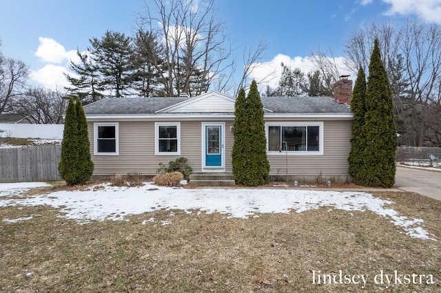 single story home with a shingled roof, a chimney, and fence