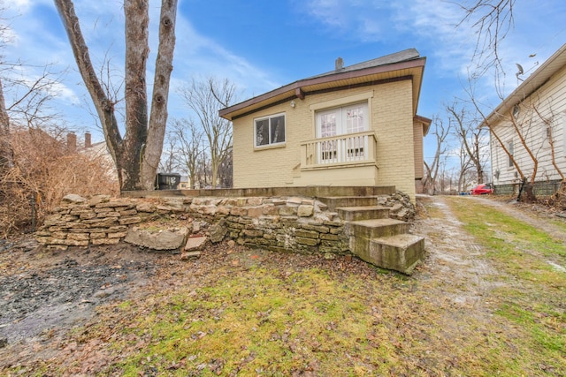 back of house featuring dirt driveway and brick siding