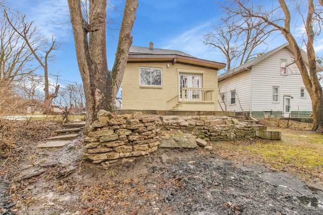 back of property with a chimney, fence, and brick siding