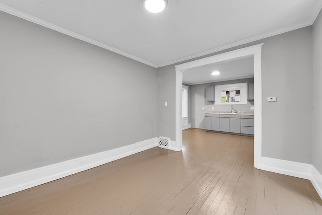 interior space with ornamental molding, a sink, and baseboards