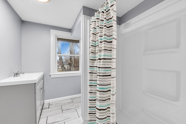 bathroom with marble finish floor, curtained shower, vanity, and baseboards